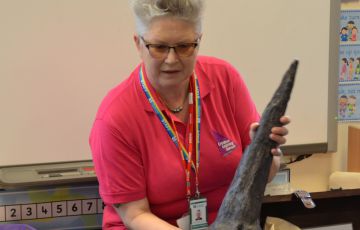 Photo of a workshop leader with a dinosaur fossil