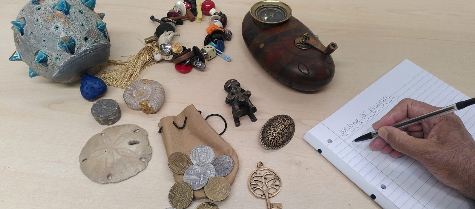 Photo of a hand writing and some artefacts