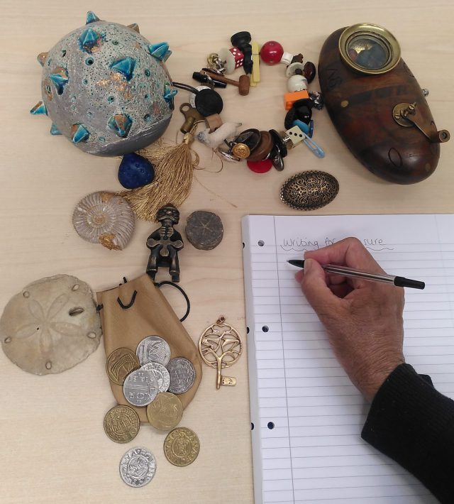 Photo of a hand writing and some artefacts