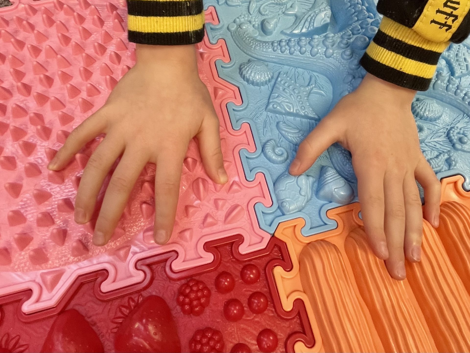 Image of hands touching sensory tiles