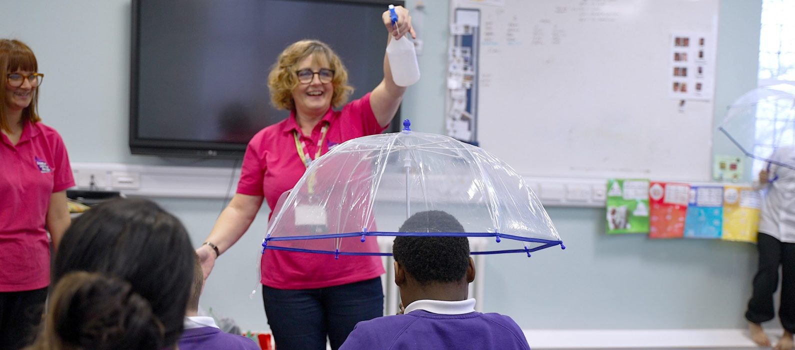 Teacher spraying an umbrella with water