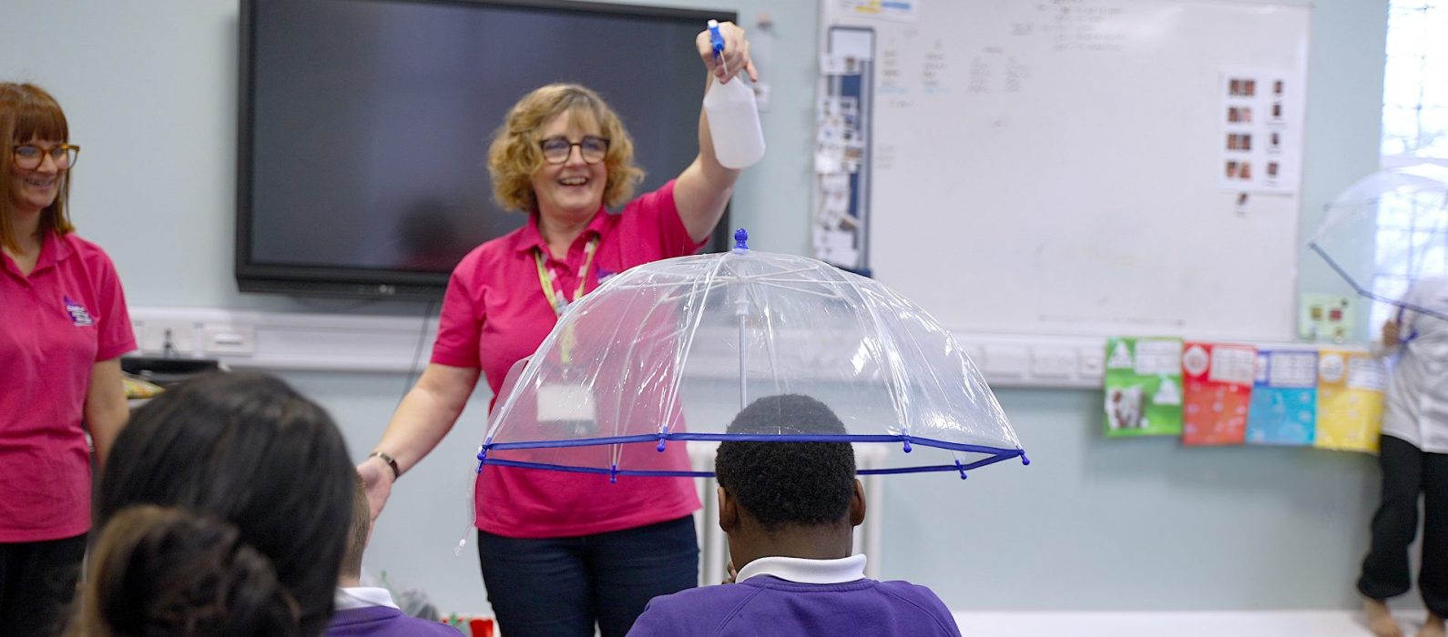 Teacher spraying an umbrella with water