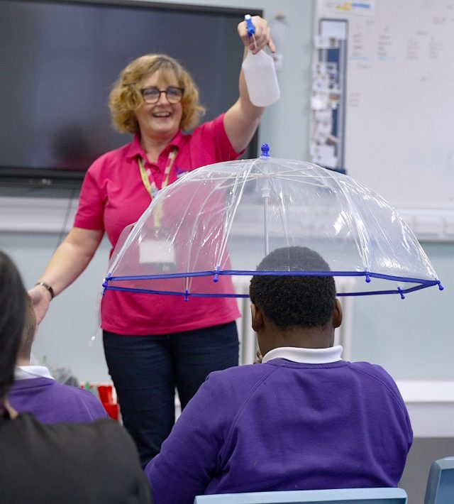 Teacher spraying an umbrella with water